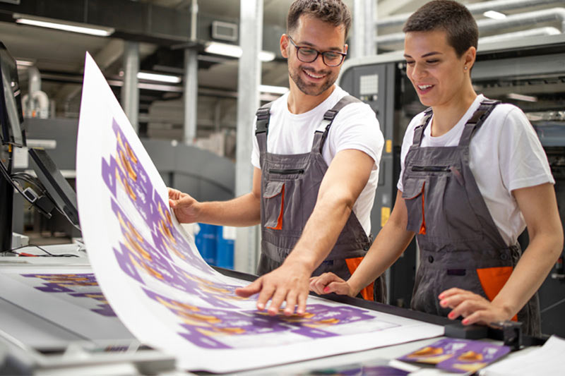 A print professional inspecting the print with a customer